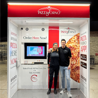 A man and woman standing together inside the Pizzaforno outdoor kiosk.