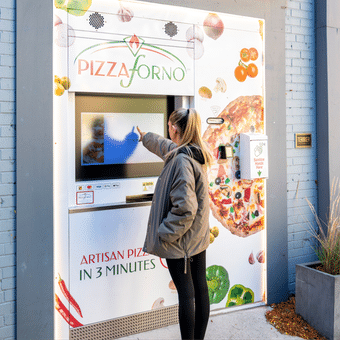 A picture of a lady using the Pizzaforno ATM kiosk.