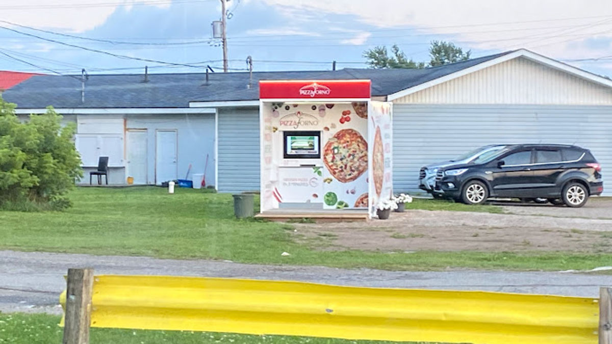 A picture taken from the side of the road that shows the PizzaForno automated pizzeria that is located in Little Current.