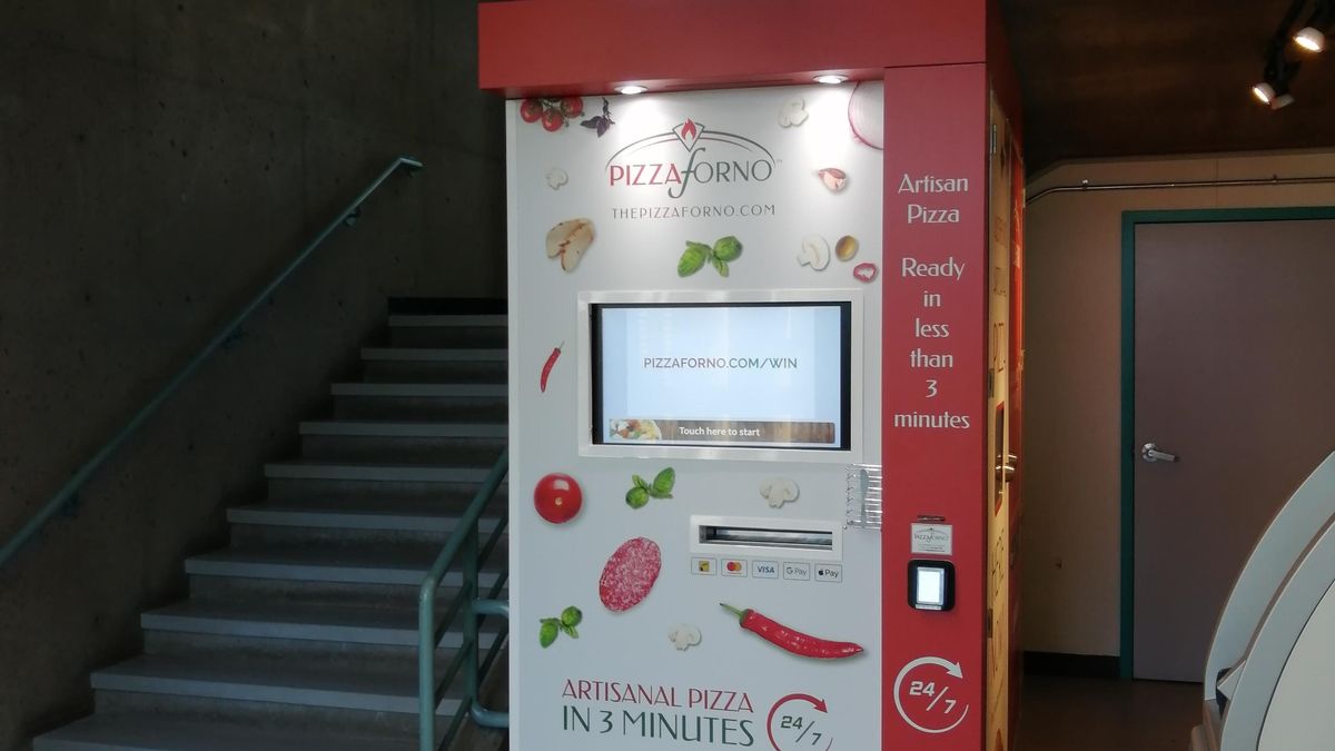 The inside of a building at Camosun College that has an automated pizza vending machine located beside the staircase.